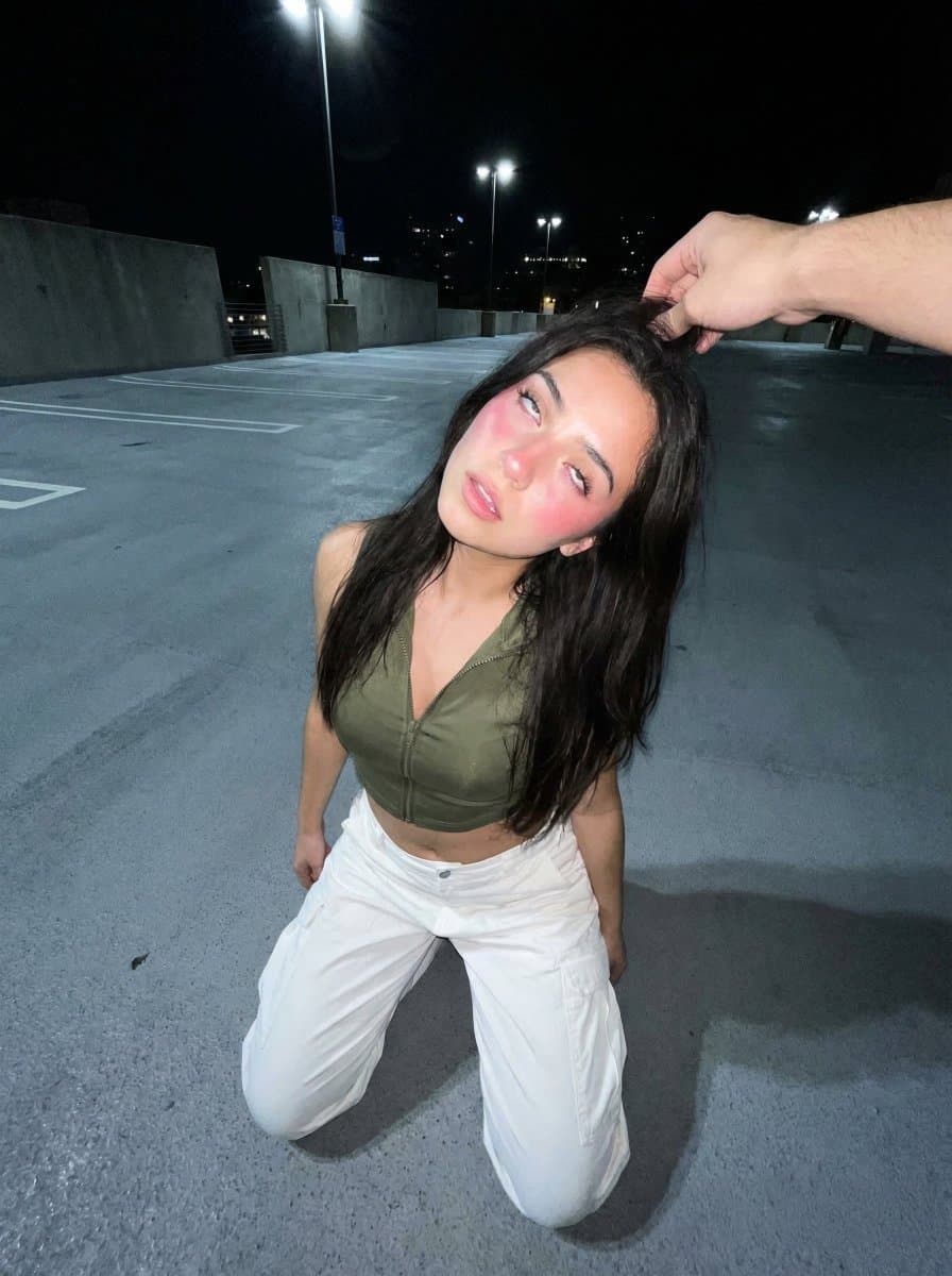 Young Woman Kneeling on Asphalt with External Hand
